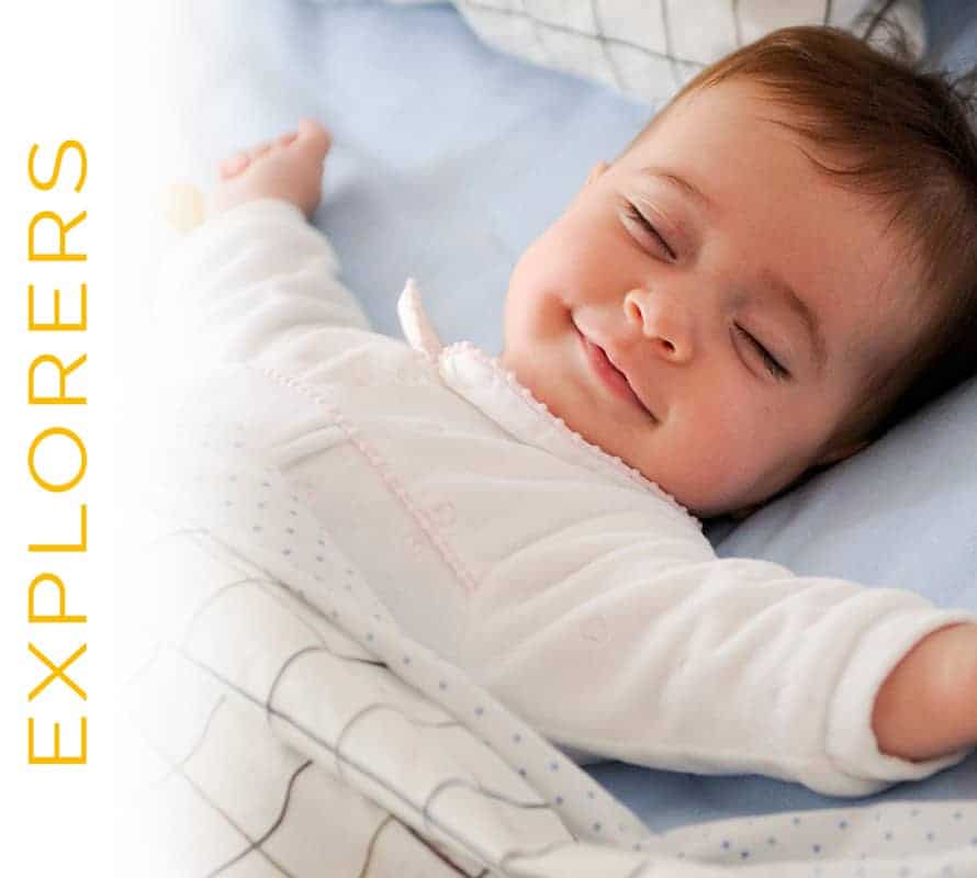 A smiling baby wearing a white outfit lying on a blue blanket with the word "explorers" in white text at the top left.