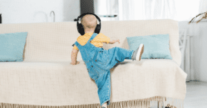 Toddler wearing headphones climbing on chair