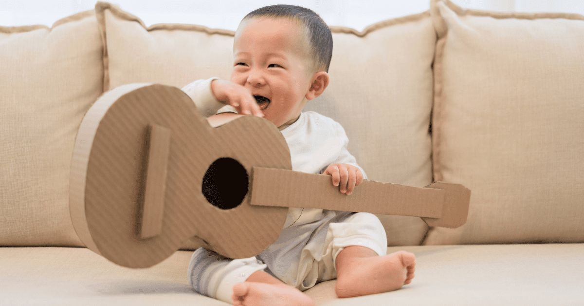 toddler holding cardboard guitar