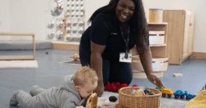 nursery practitioner smiling with a baby in nursery