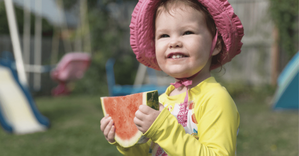 child holding watermelon smiling