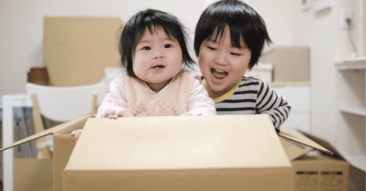 toddler and baby with cardboard box