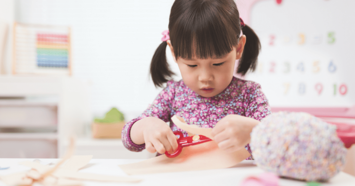 toddler cutting paper with scissors