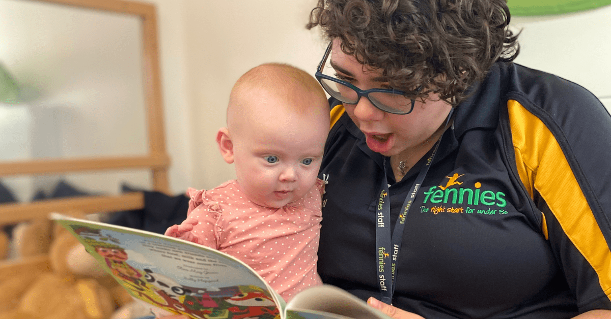 nursery practitioner reading a book to a baby