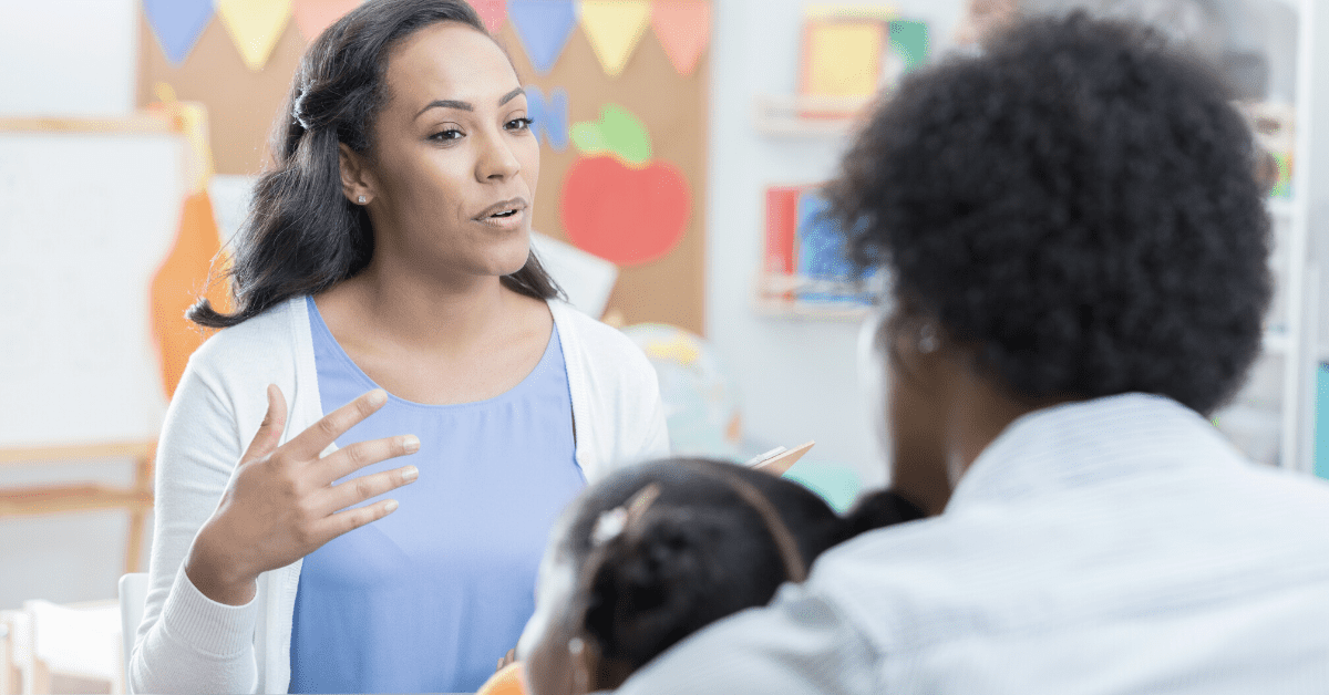 teacher talking to child and parent in classroom