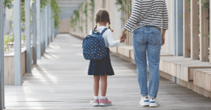 child and parent holding hands outside school