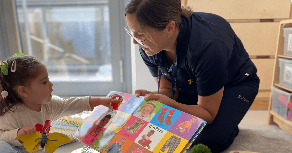 practitioner and child reading a book in nursery