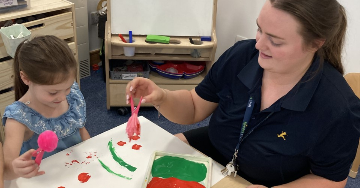 early years teacher painting with child