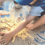 children's hands in sand tray